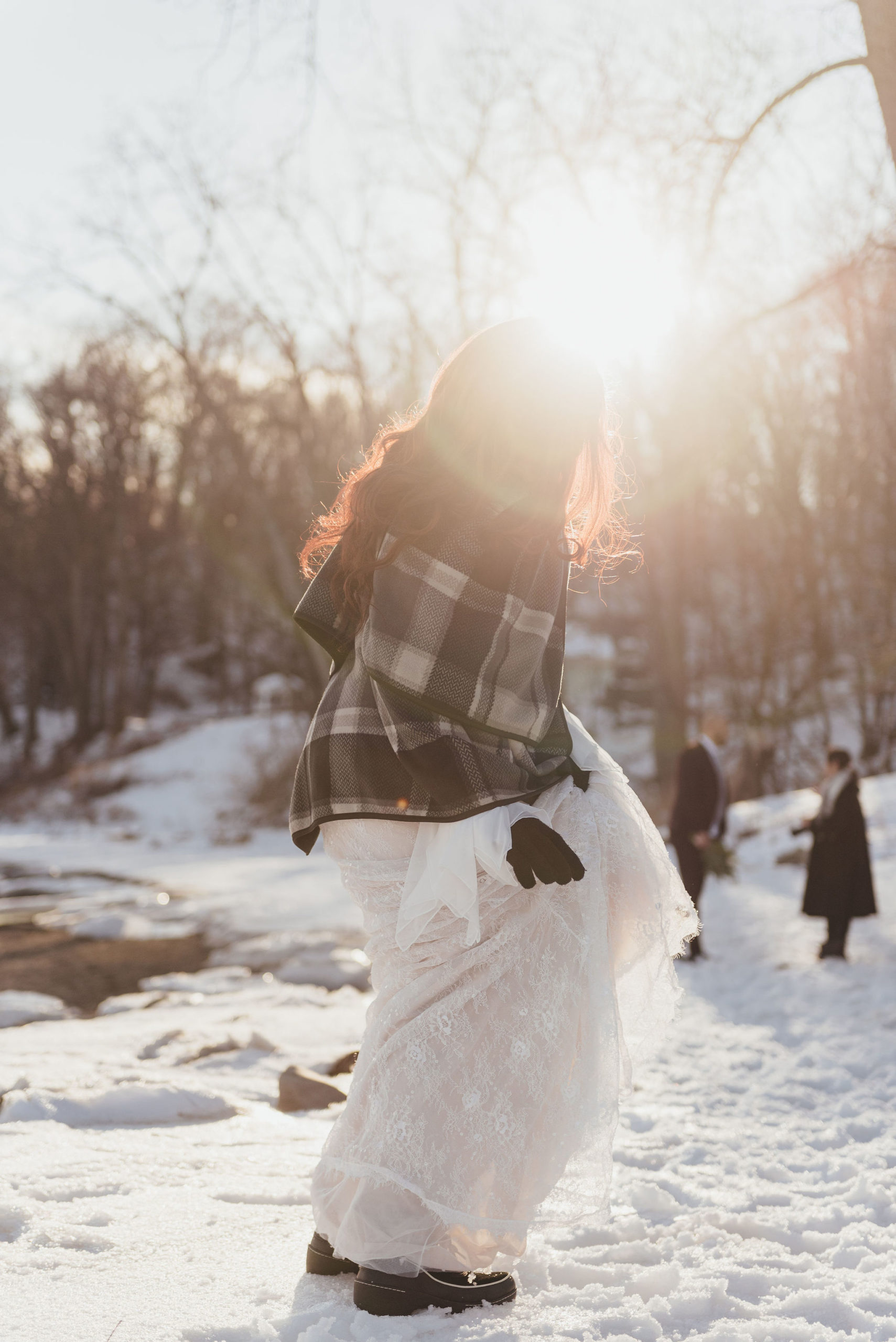 bride walking away with a black plaid scarf in the snow