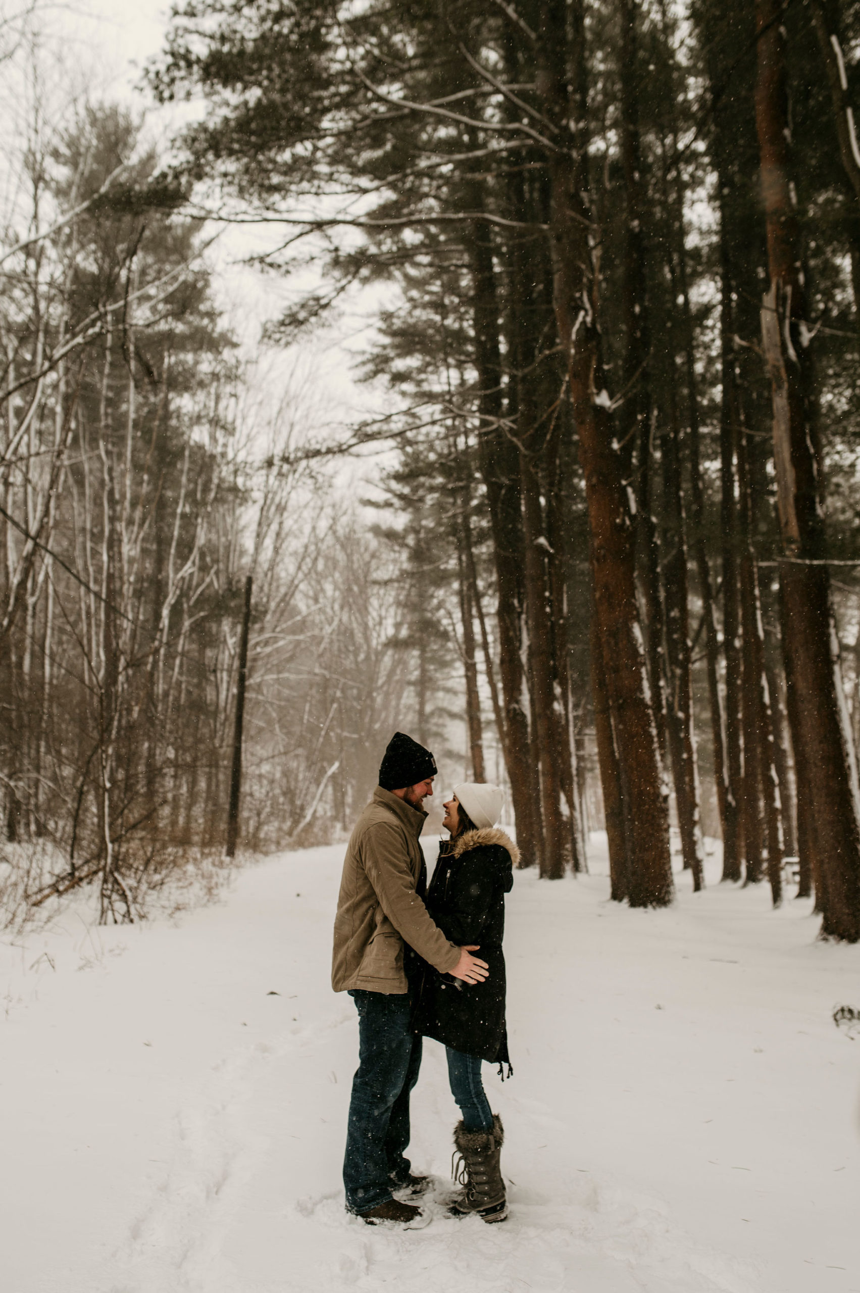 couples in a forest hugging in the snow | Tips For Your New York Winter Engagement or Elopement