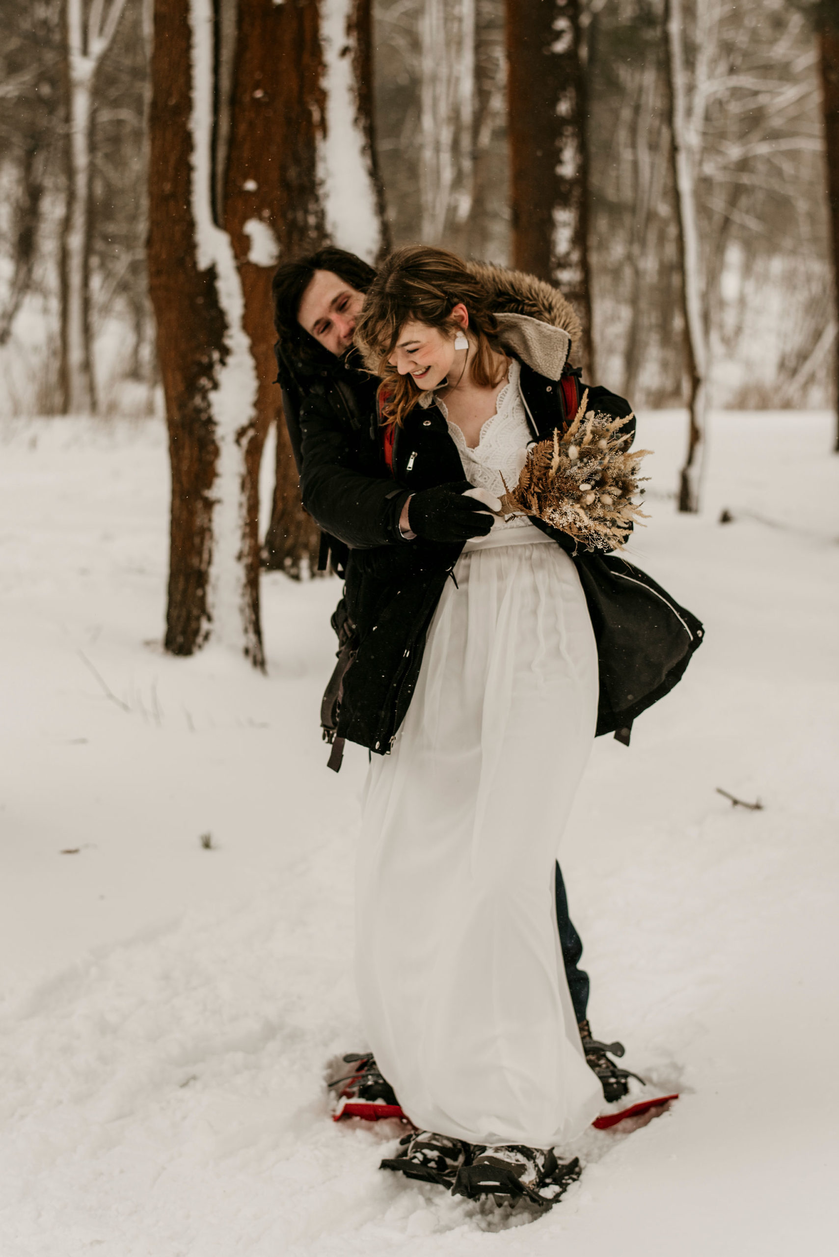 groom hugging bride from the back in a snowy forest | Tips For Your New York Winter Engagement or Elopement