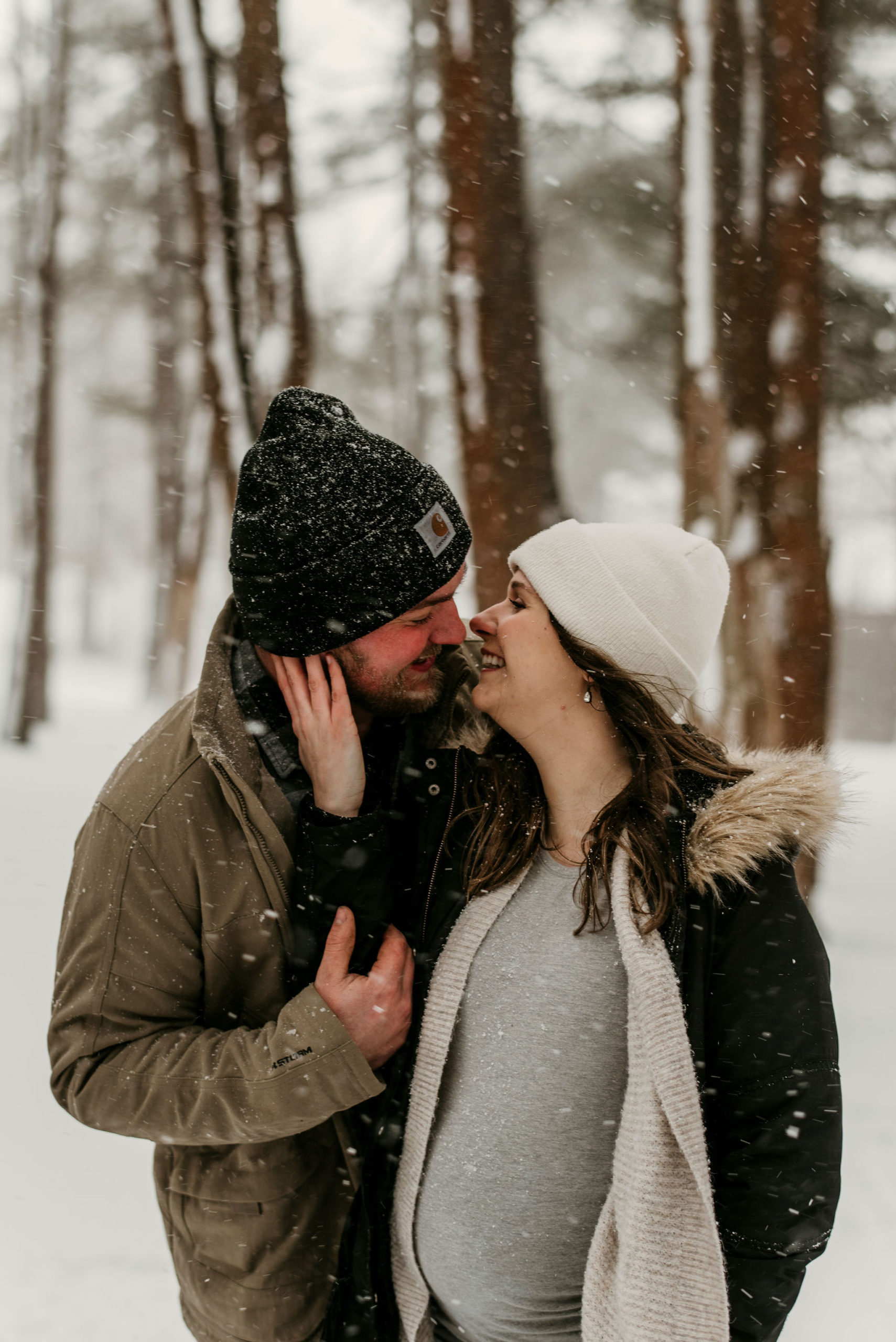 couple looking at eachother and kissing in a snowy forest