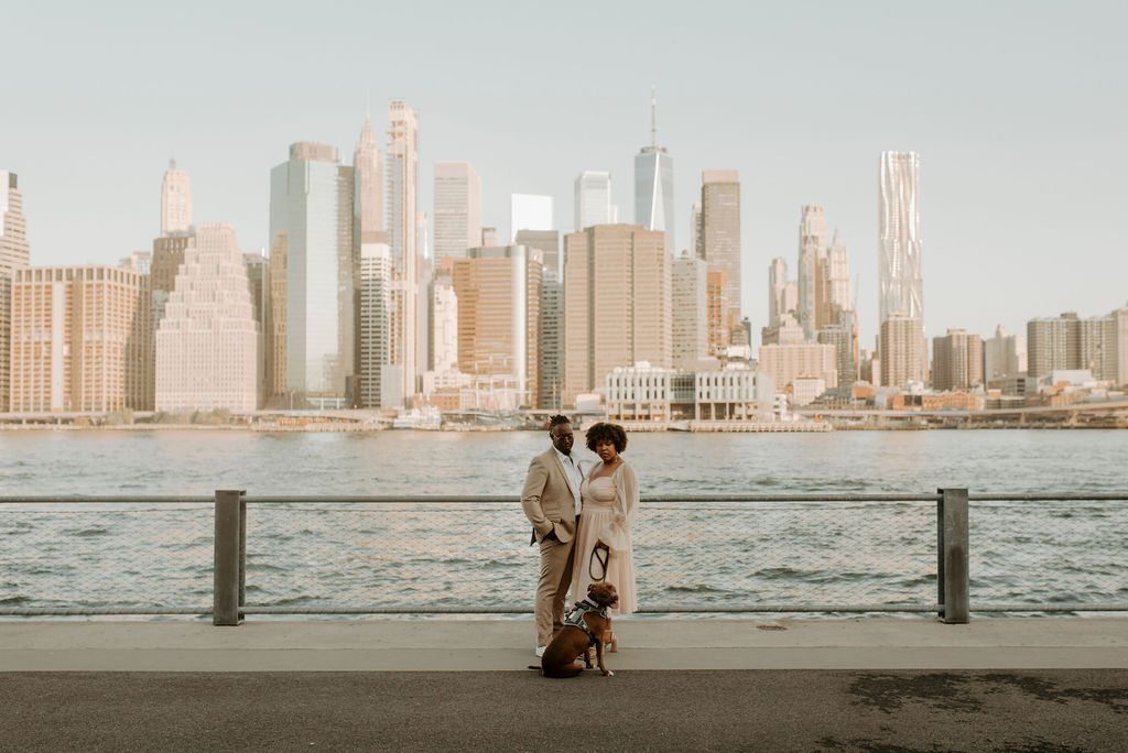 couple posing near river walking their dog in new york