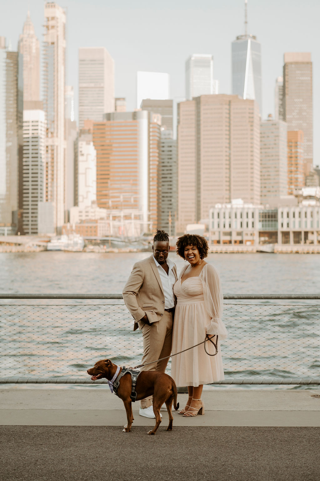 couple posing for a picture near new york river walking their dog