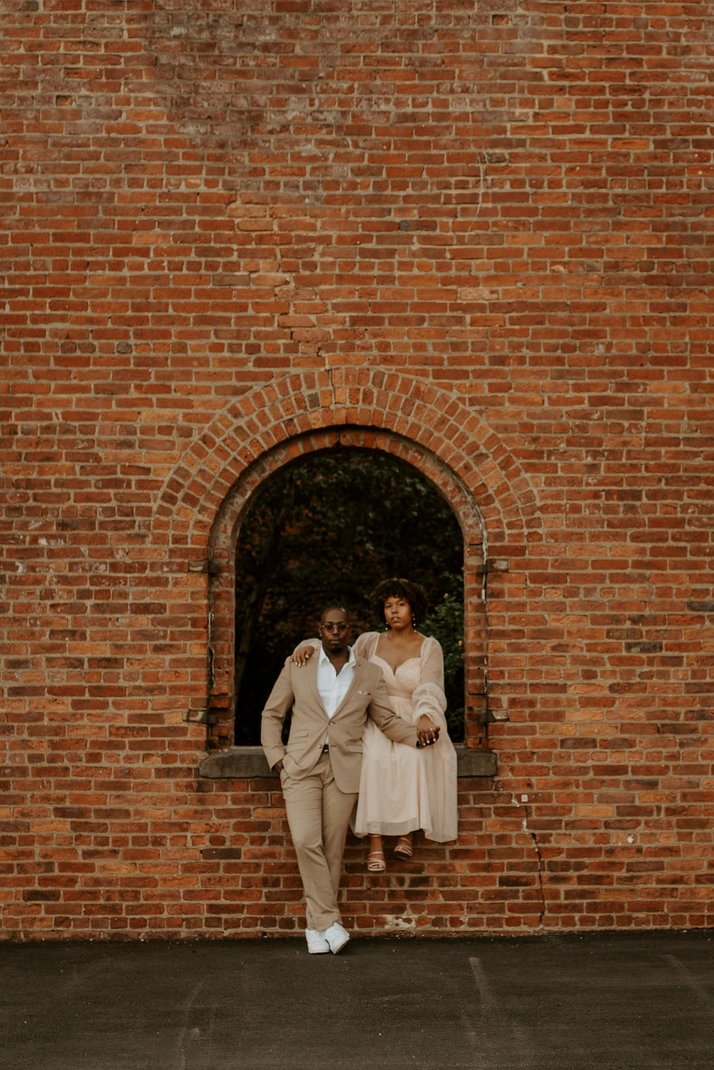 couple sitting near a brick wall posing in brooklyn