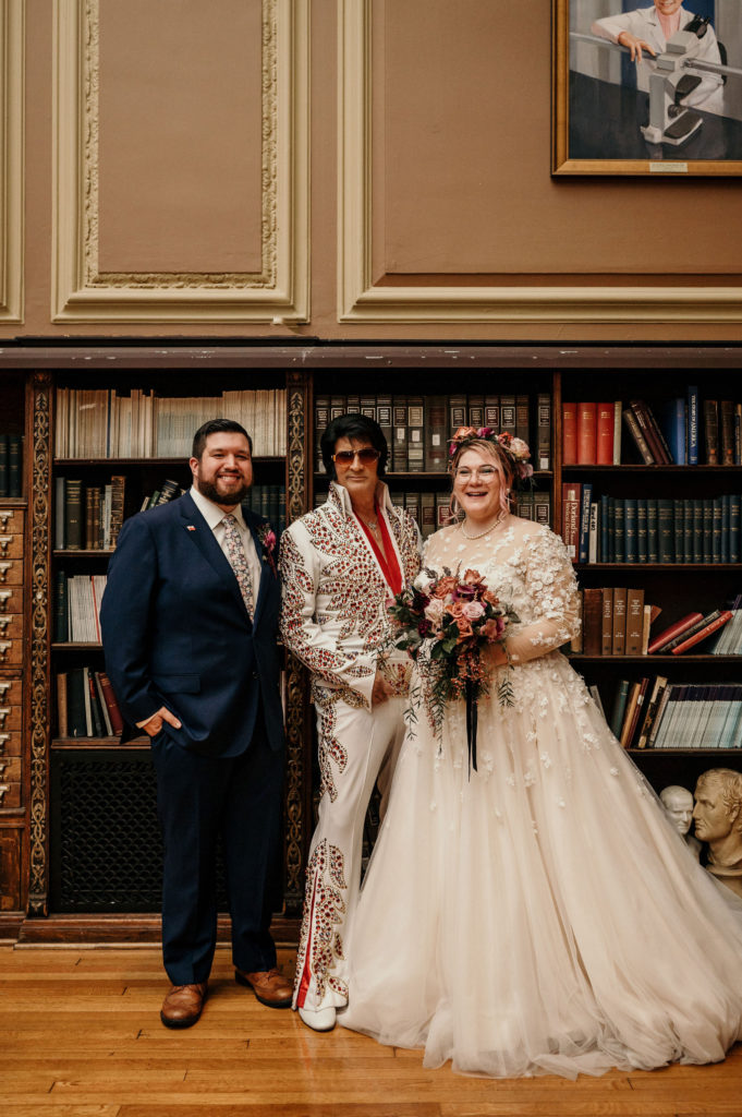 Bride and groom posing with Elvis officiant after wedding in PA at The Mütter Museum
