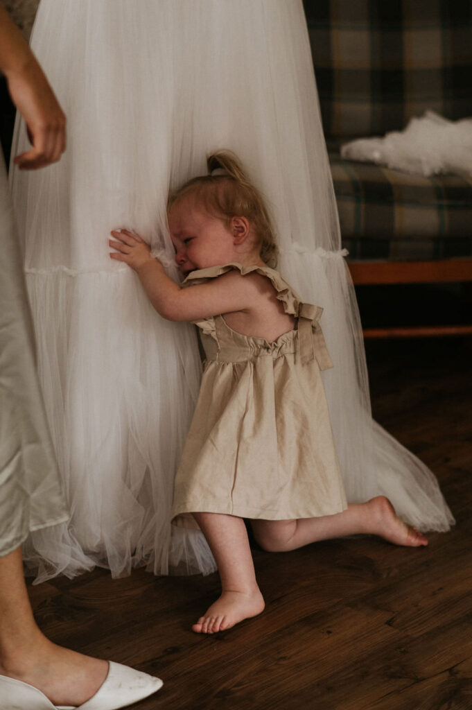 Daughter hugging bride while crying.