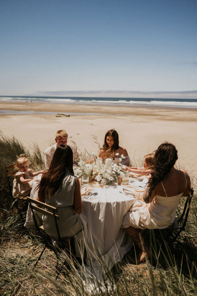 Family enjoying meal during couple's elopement at the beach.