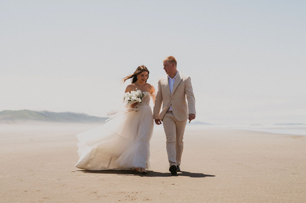 Bride and groom walking in the beach during their intimate beach elopement.