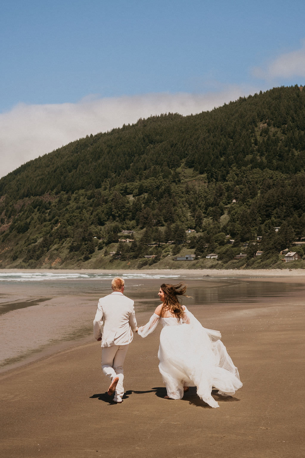Bride and Groom at their elopement running in the beach.