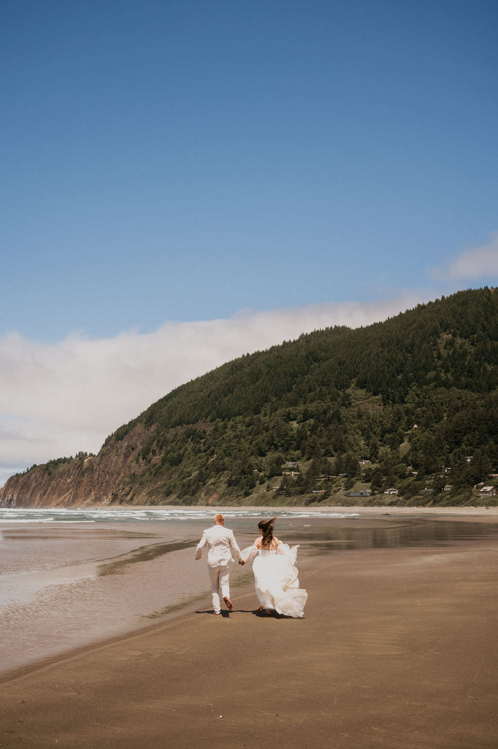 Bride and Groom at their elopement running in the beach.