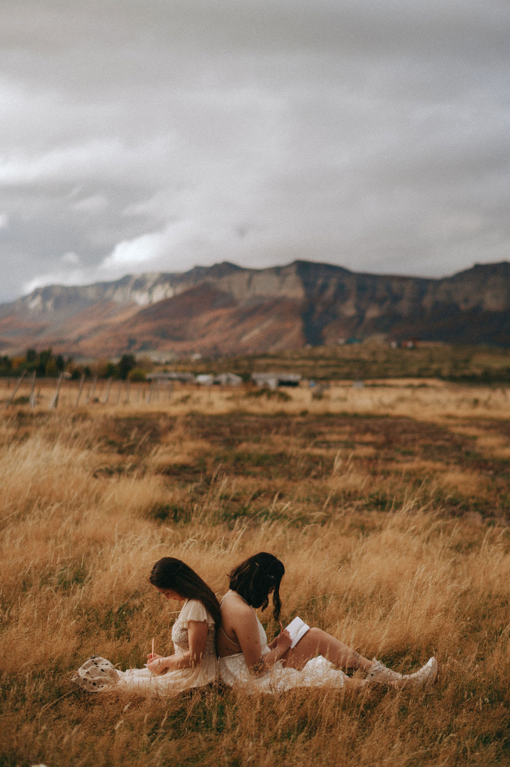 Couple writing their vows sitting back to back for their intimate Patagonia elopement.