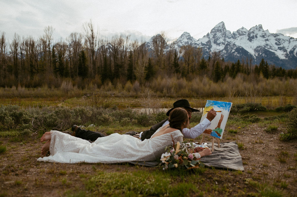 Couple painting a mountain scene during their Patagonia elopement, enjoying unique elopement activities in nature.